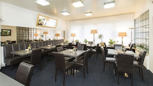 A hotel dining area with multiple tables and booths, equipped with lamps and potted plants. - Hansa Hotel (Düsseldorf)