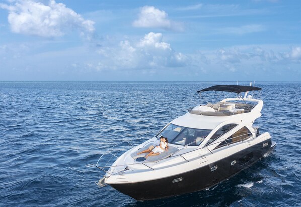 A yacht with a covered seating area, a cabin, and a helipad.
