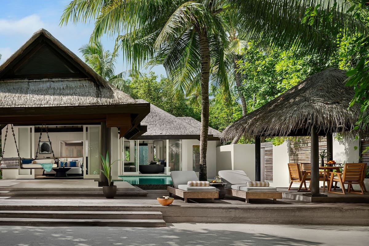 A resort with a thatched-roof structure, outdoor seating, and a pool area.