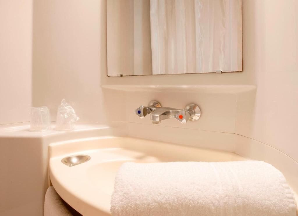 A bathroom with a sink, a mirror, and a towel.