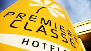 Un panneau jaune sur lequel on peut lire les mots « HÔTELS DE PREMIÈRE CLASSE » et qui arbore un symbole de fleur de lys blanche.