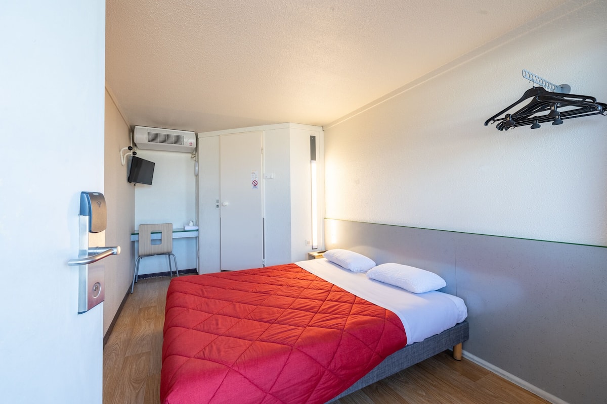 Een hotelkamer met een bed, een bureau en een stoel.