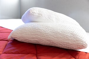 Dos almohadas sobre una cama con colcha roja.