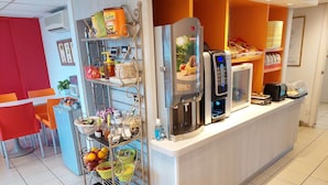 A breakfast bar with a coffee machine, a water dispenser, and a fruit basket. - Premiere Classe Saintes (Saintes)