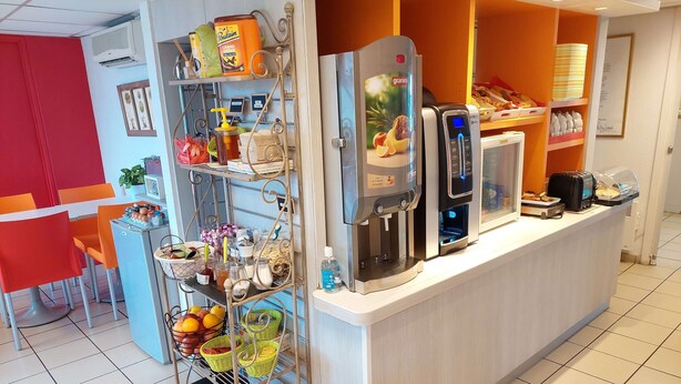 A breakfast bar with a coffee machine, a water dispenser, and a fruit basket. - Premiere Classe Saintes (Saintes)