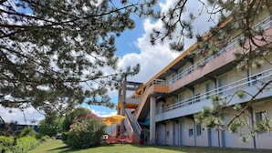 A building with a multi-level structure, outdoor seating area, and a staircase leading to an upper level. - Premiere Classe Saintes (Saintes)