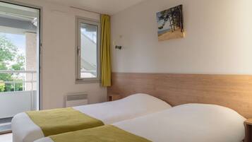 Habitación de hotel con dos camas, una ventana con cortina, un cuadro colgado en la pared y una mesita de noche.