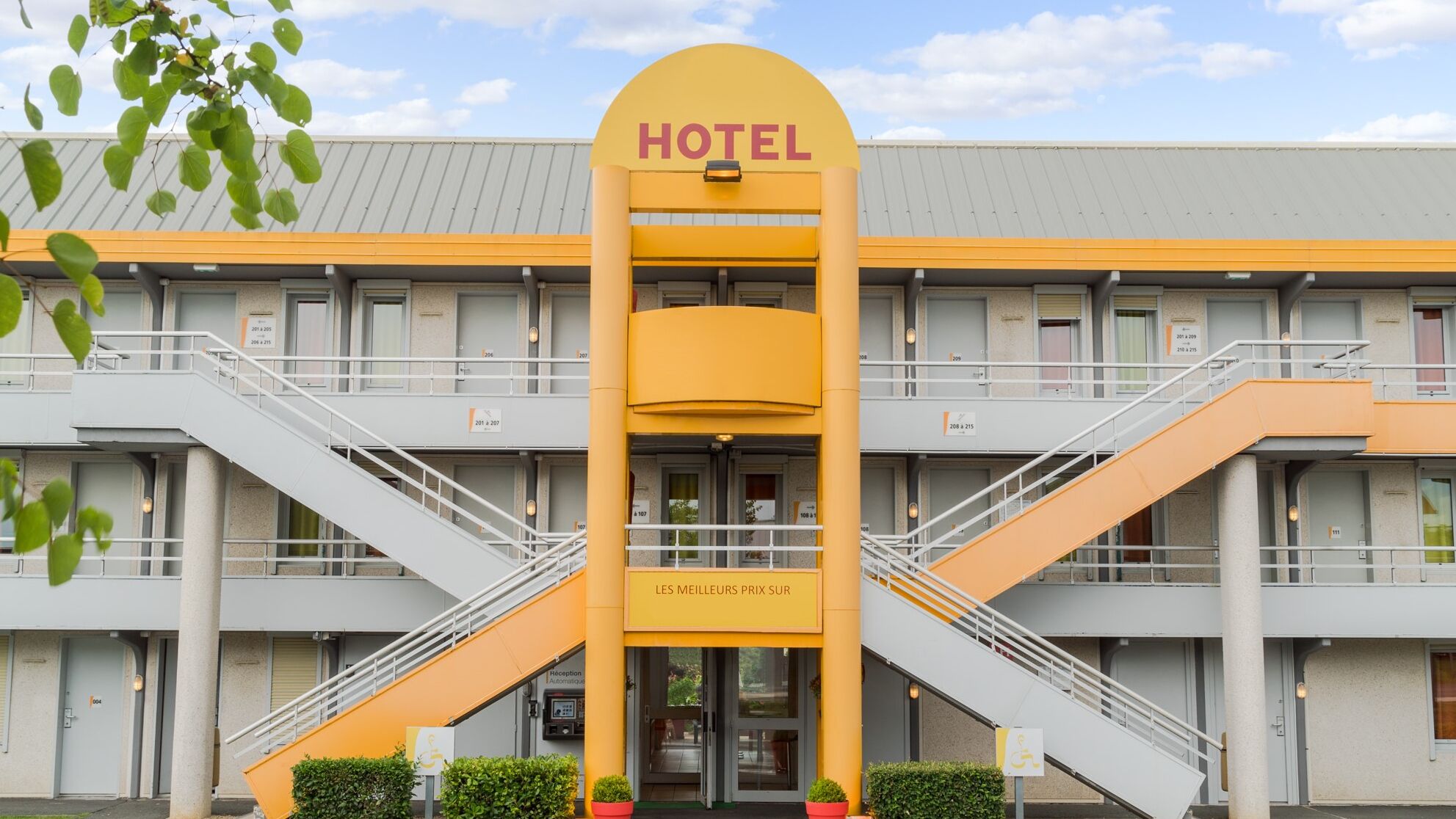 Un hôtel reconnaissable à son arc jaune imposant et à une enseigne indiquant « HÔTEL » en haut.