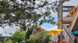 A building with a staircase, outdoor seating, and a car parked nearby. - Premiere Classe Saintes (Saintes)