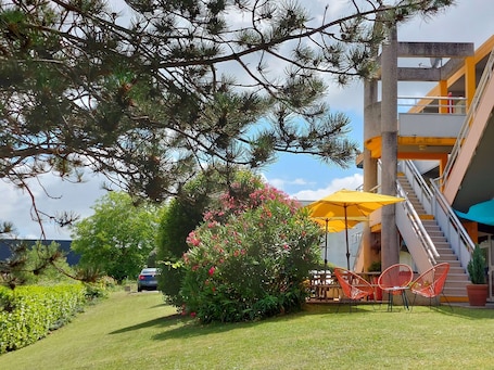 A building with a staircase, outdoor seating, and a car parked nearby.