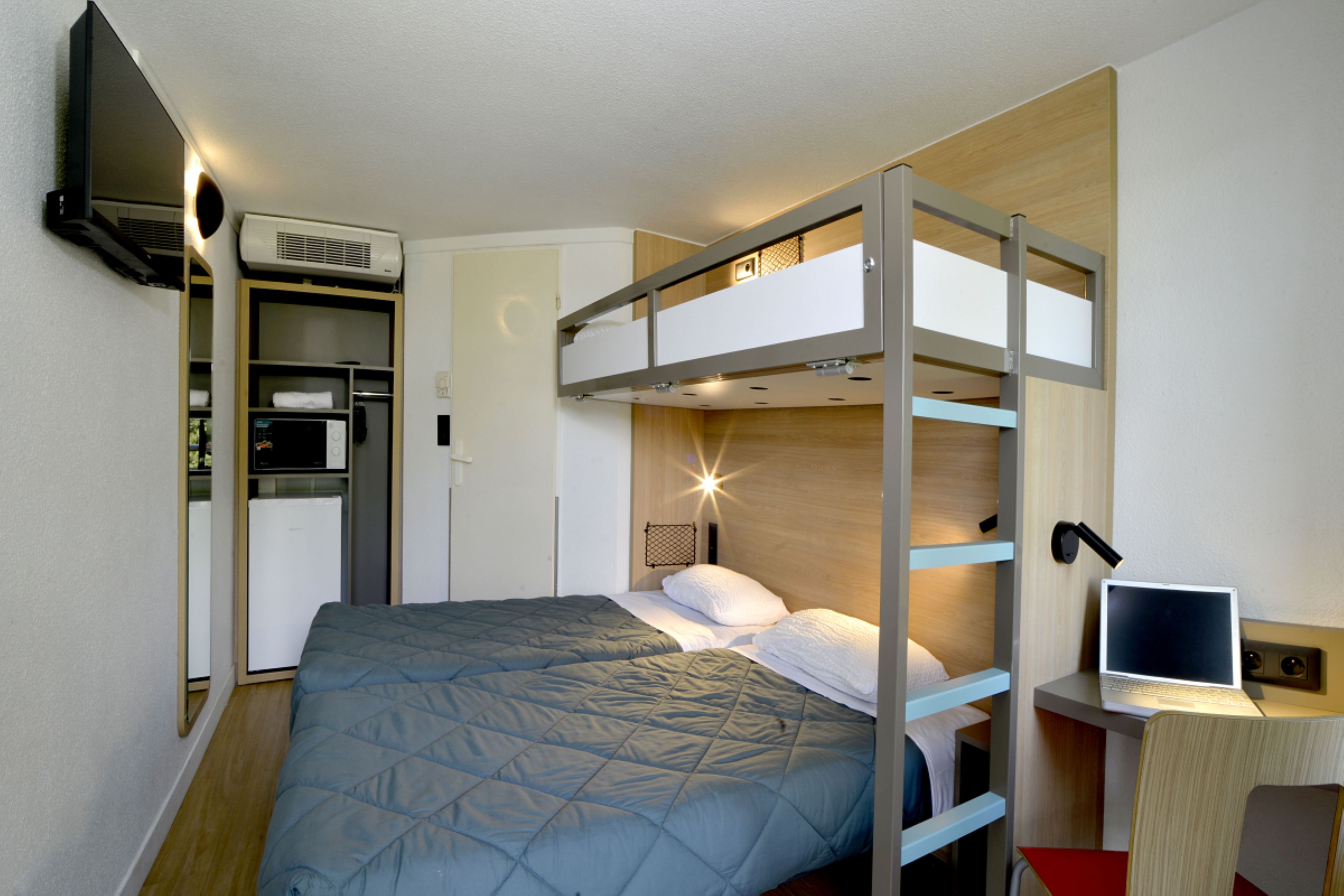A bunk bed room with a desk and a television.