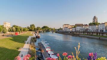 A riverside view with boats docked, a bridge, and historic buildings.