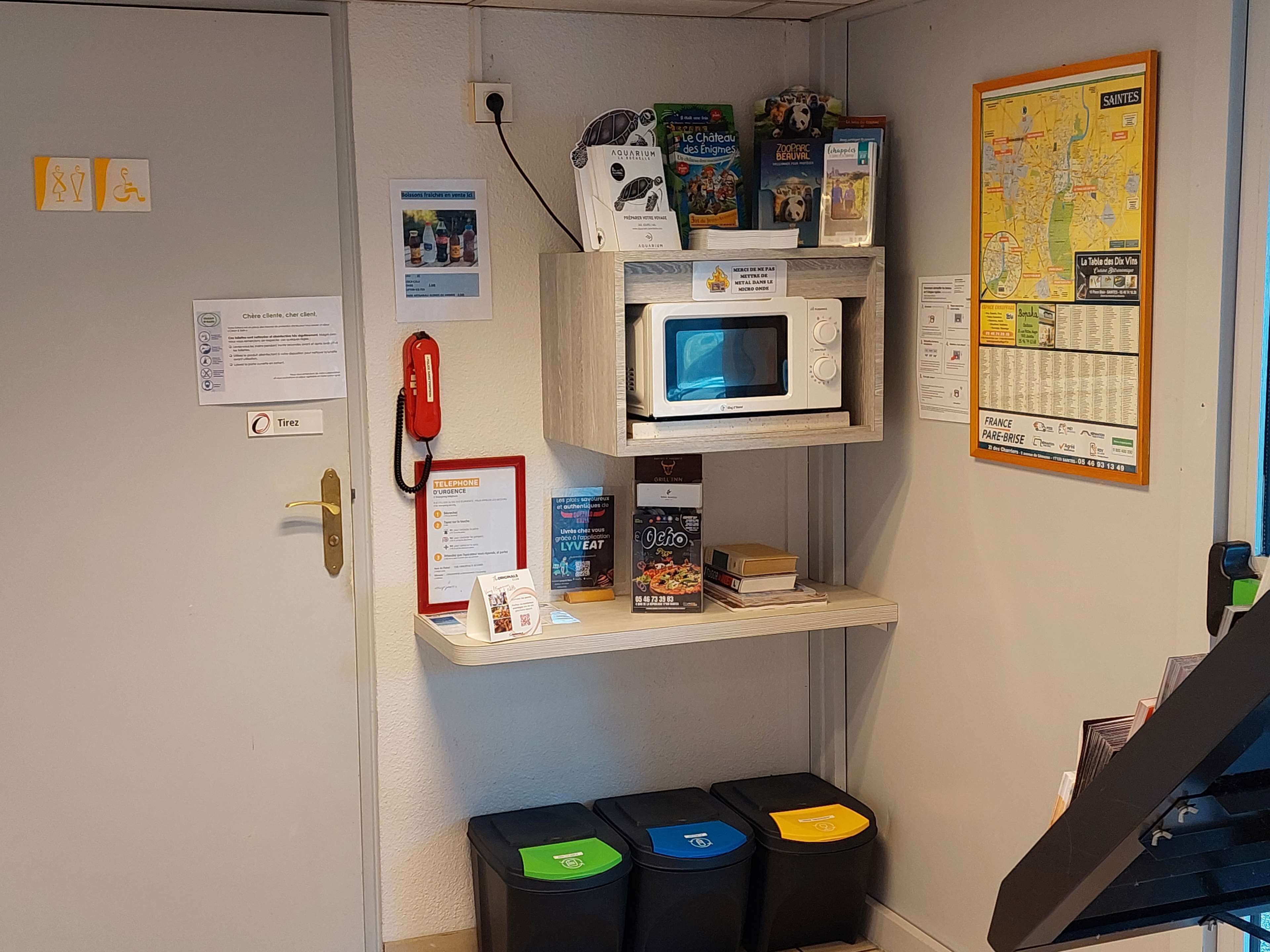 Une chambre d’hôtel équipée d’un téléphone, d’un plan de la ville, d’un four à micro-ondes et de poubelles.