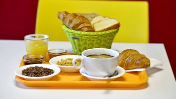 A breakfast tray with croissants, a cup of coffee, cereal, and a glass of juice.