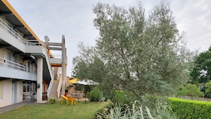 A courtyard with a staircase, outdoor seating, and a large tree. - Premiere Classe Saintes (Saintes)
