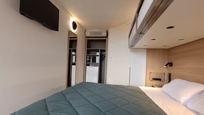A modern hotel room with a bed, a wardrobe, and a built-in air conditioning unit. - Premiere Classe Saintes (Saintes)