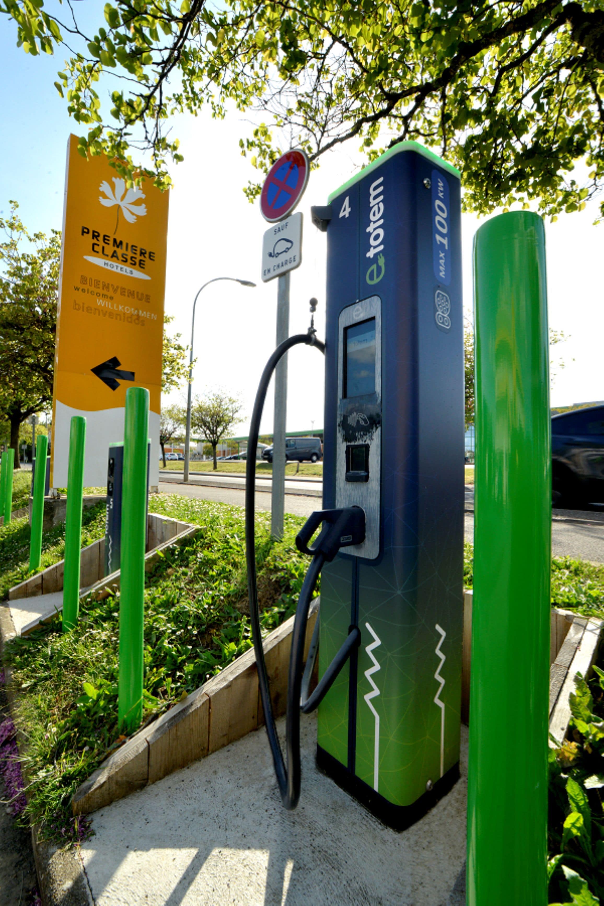 A green electric vehicle charging station with a sign indicating a 4-hour parking limit.