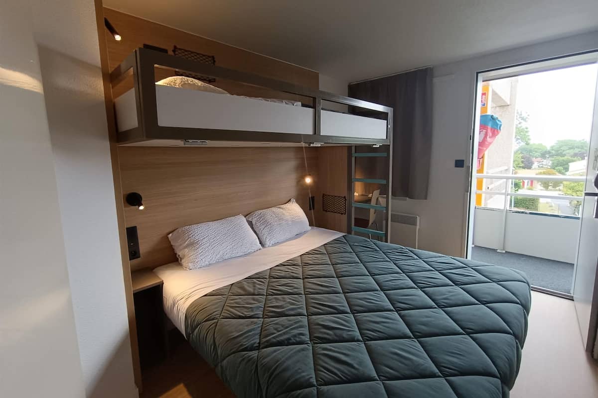 Una habitación de hotel moderna con literas, un escritorio y un balcón con vistas.