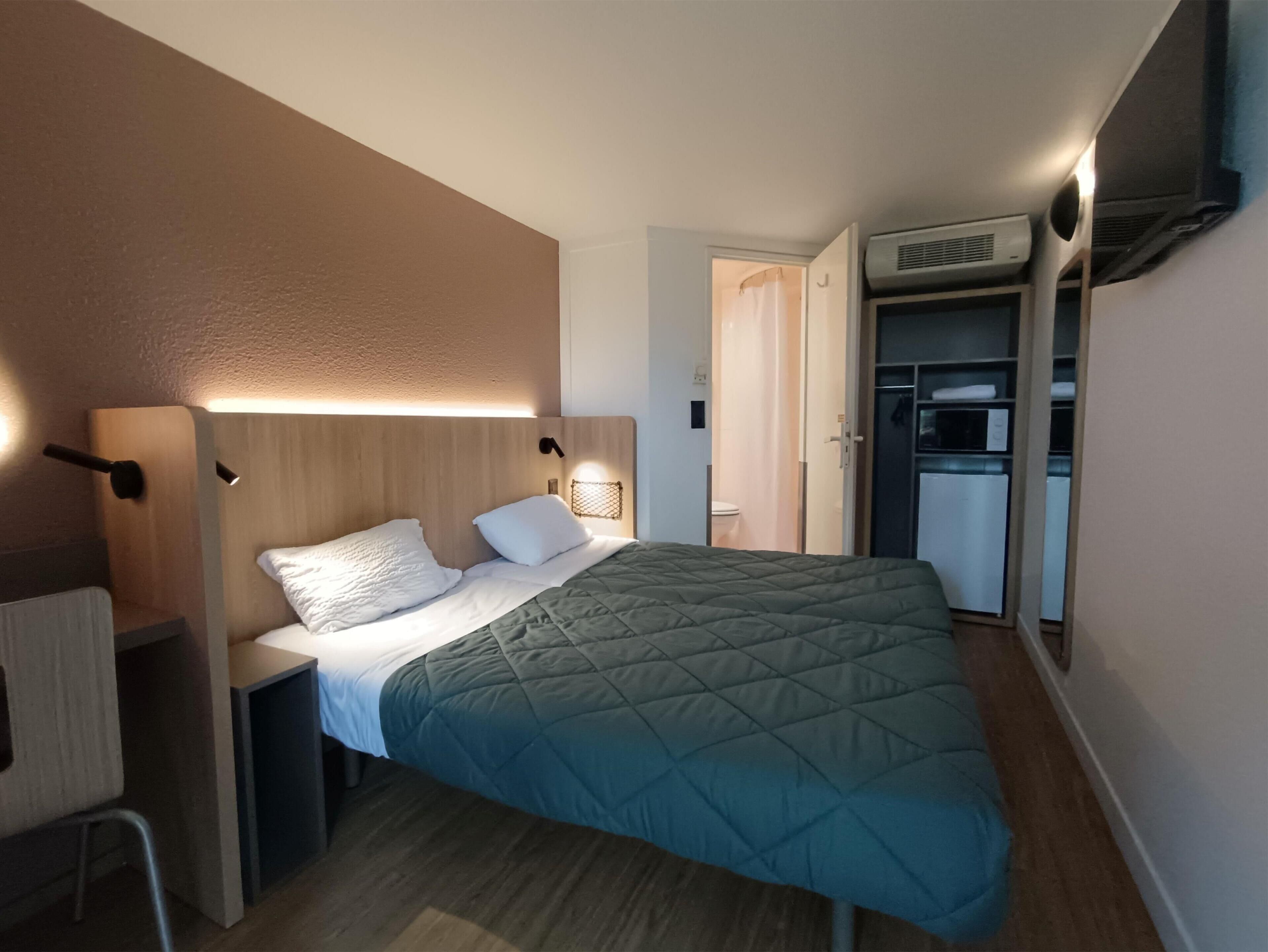 Une chambre à coucher de taille réduite, comprenant un lit, des tables de chevet, une armoire et un système de climatisation intégré.