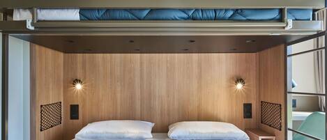 Una cama litera con cabecera de madera, dos mesitas de noche y una colcha azul acolchada.