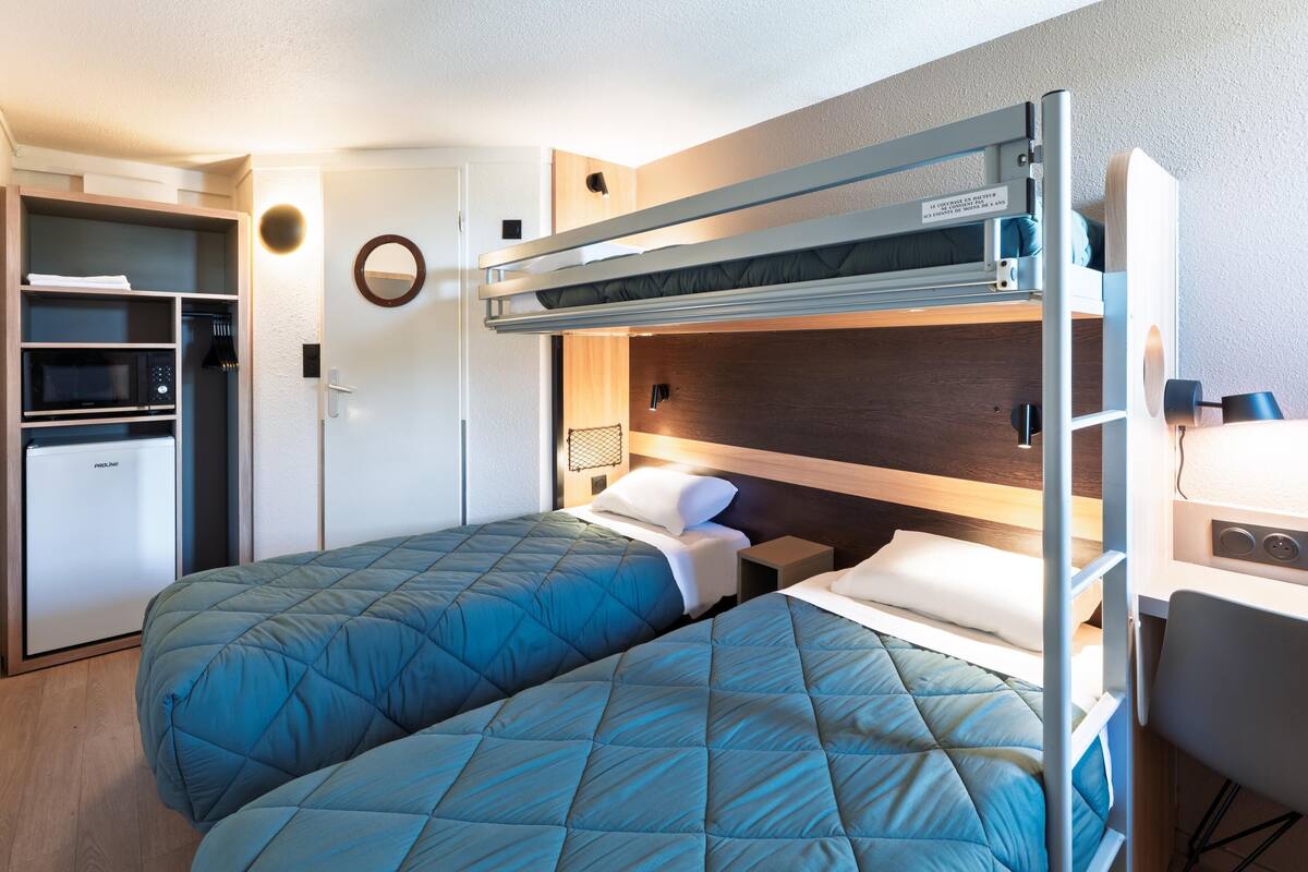 A bunk bed room with a desk and a microwave.