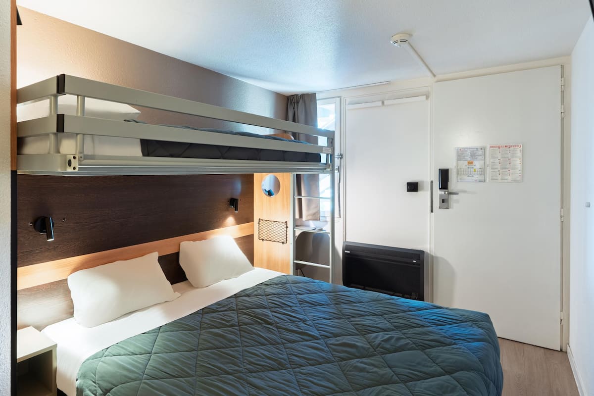 A bunk bed with a headboard, a bedside table, and a wall-mounted heater.