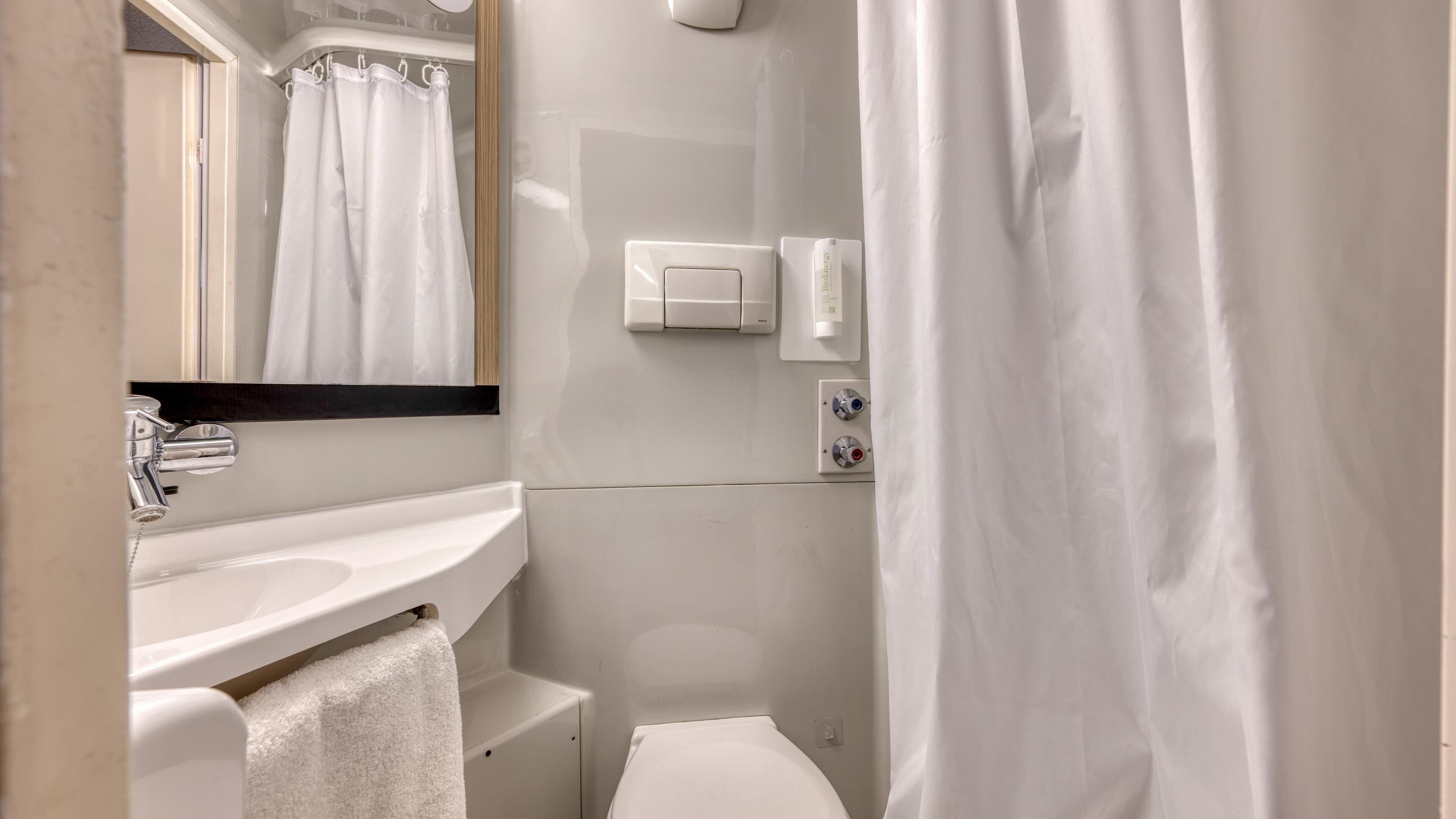 A bathroom with a white sink, mirror, and toilet.