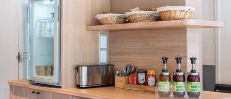 A kitchenette with a refrigerator, toaster, and condiment dispensers.