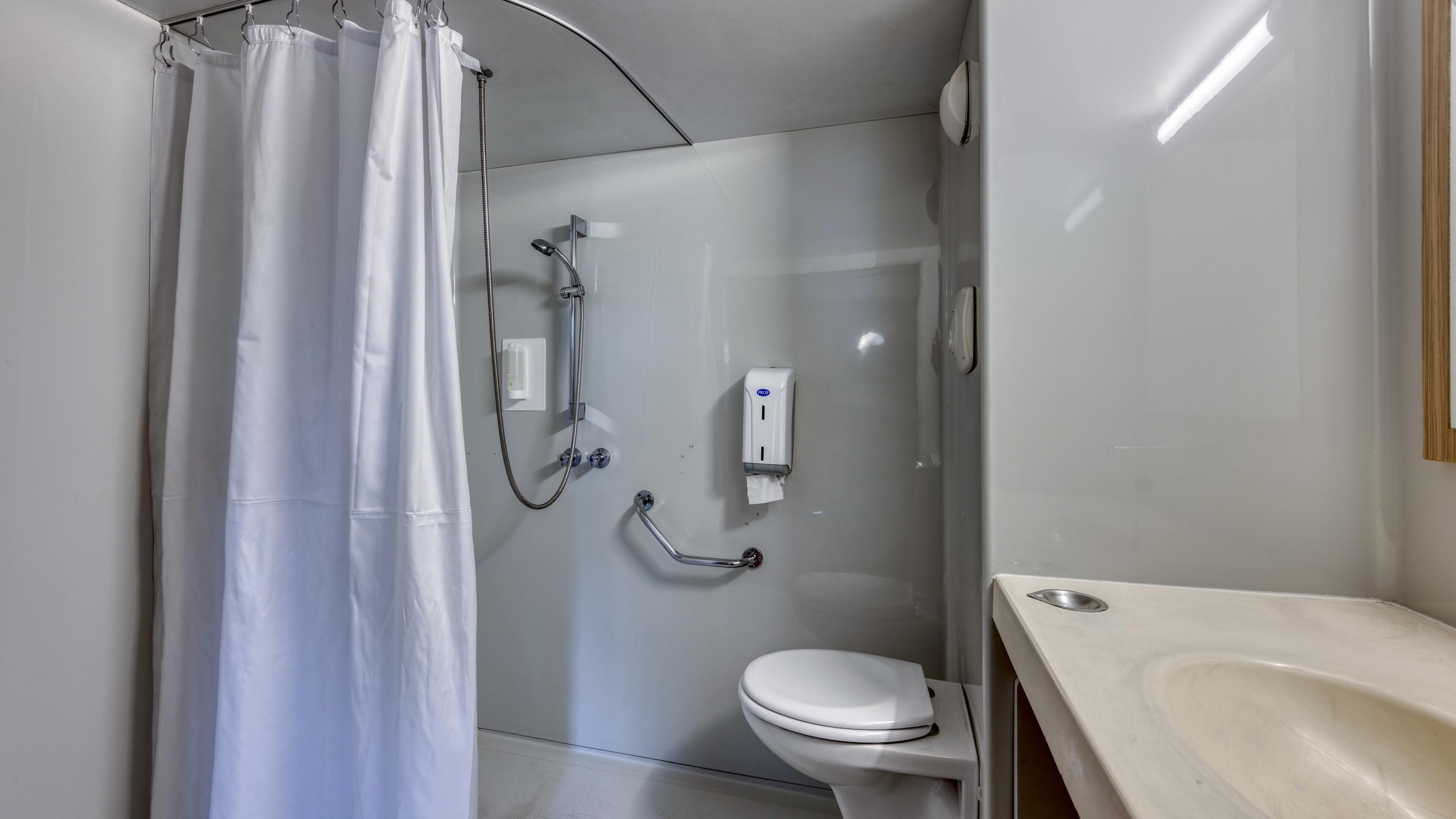 A small, modern bathroom with a shower, toilet, and sink.