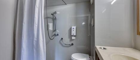 A small, modern bathroom with a shower, toilet, and sink.