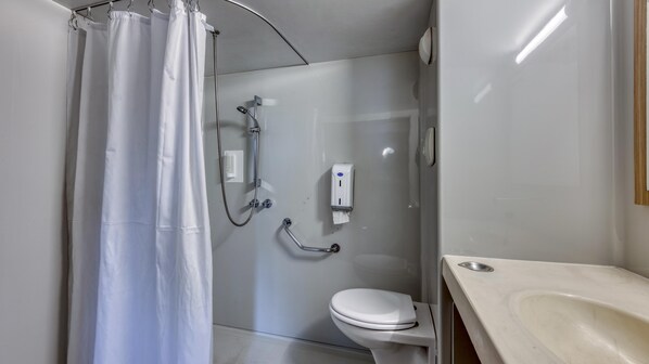 A small, modern bathroom with a shower, toilet, and sink.