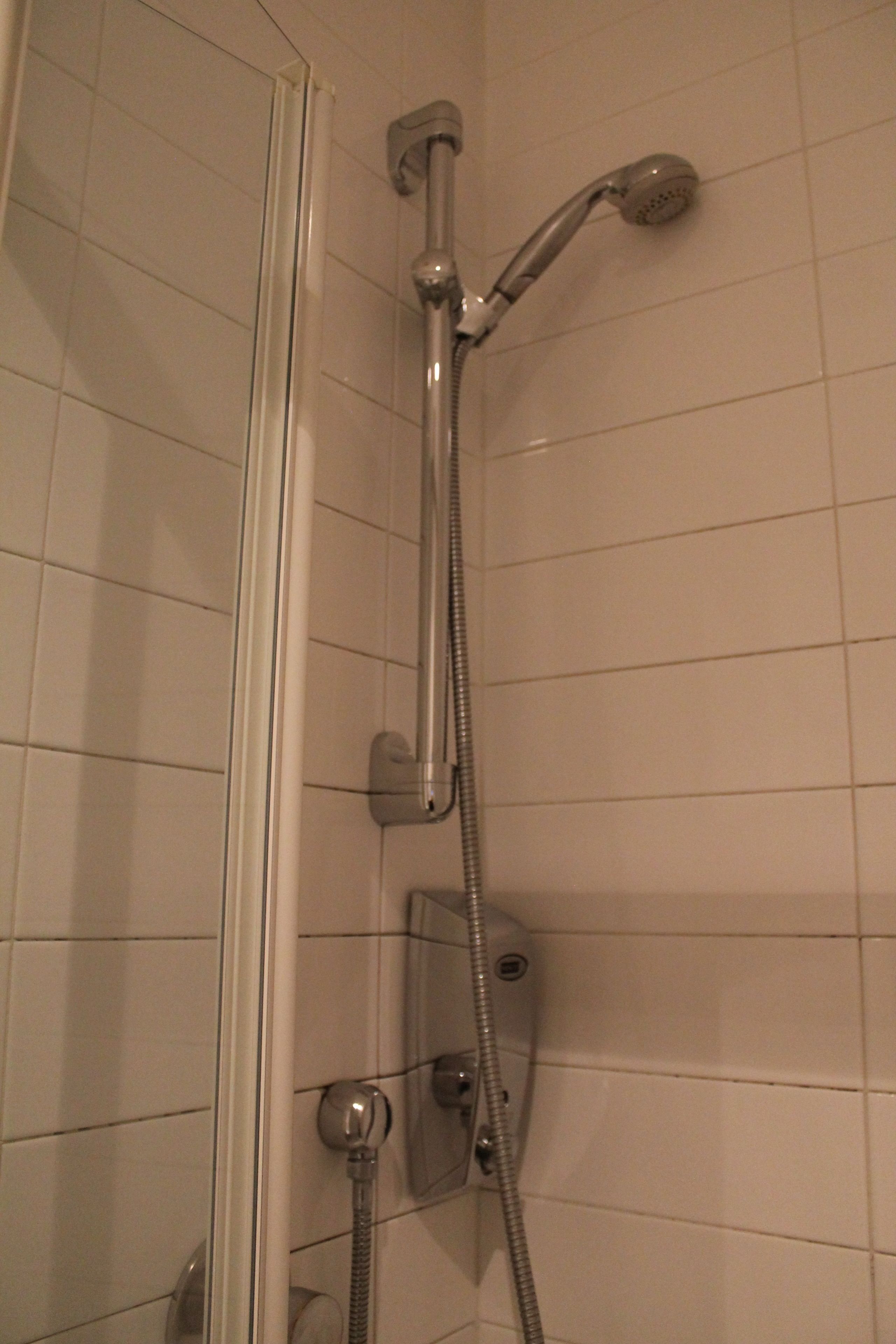 A shower with a handheld showerhead and a fixed wall-mounted showerhead.