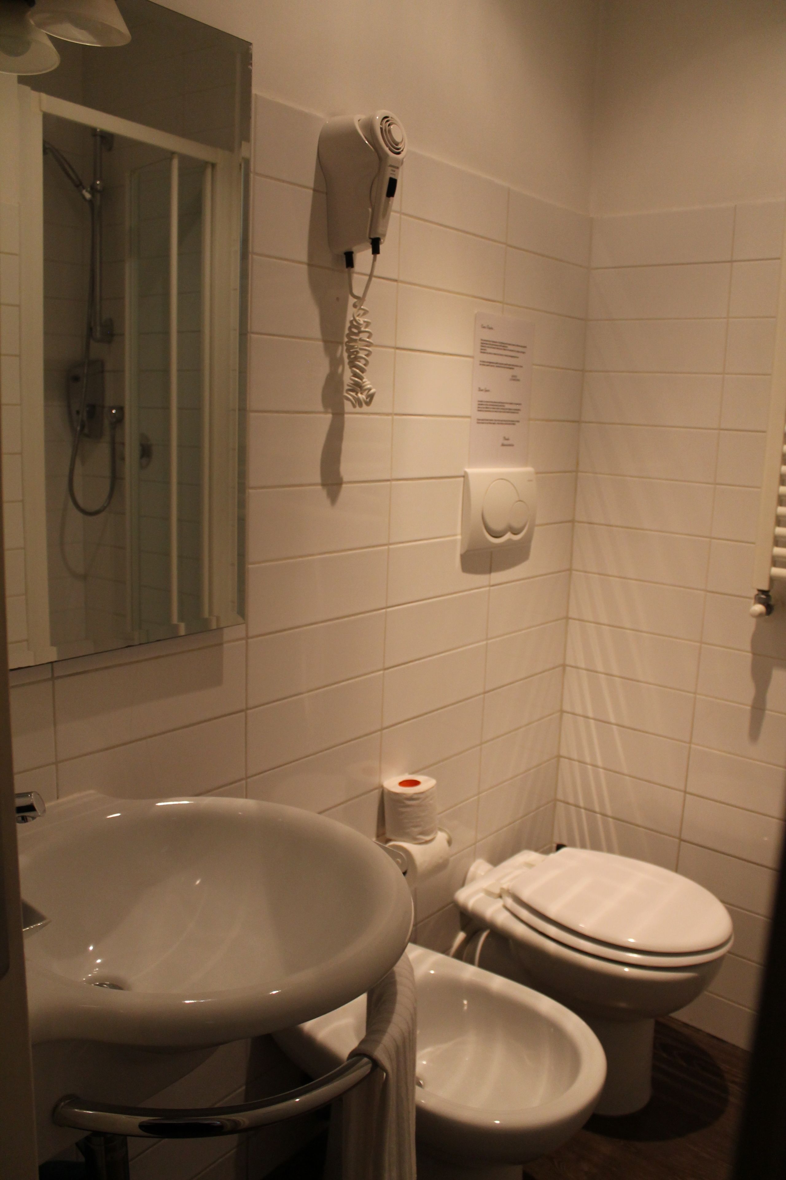 Een badkamer met een wastafel, toilet en een aan de muur bevestigde haardroger.