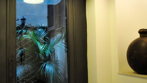 A doorway leading to a tiled patio with potted plants and a large vase on a shelf. - Relais Palazzo Taverna (Rome)