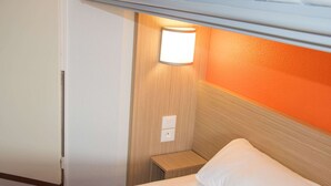 Ein Hotelzimmer mit Etagenbett, Nachttisch mit Lampe und kleinem Beistelltisch.