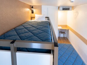 Een kleine kamer met een bed, een bureau en een stoel.