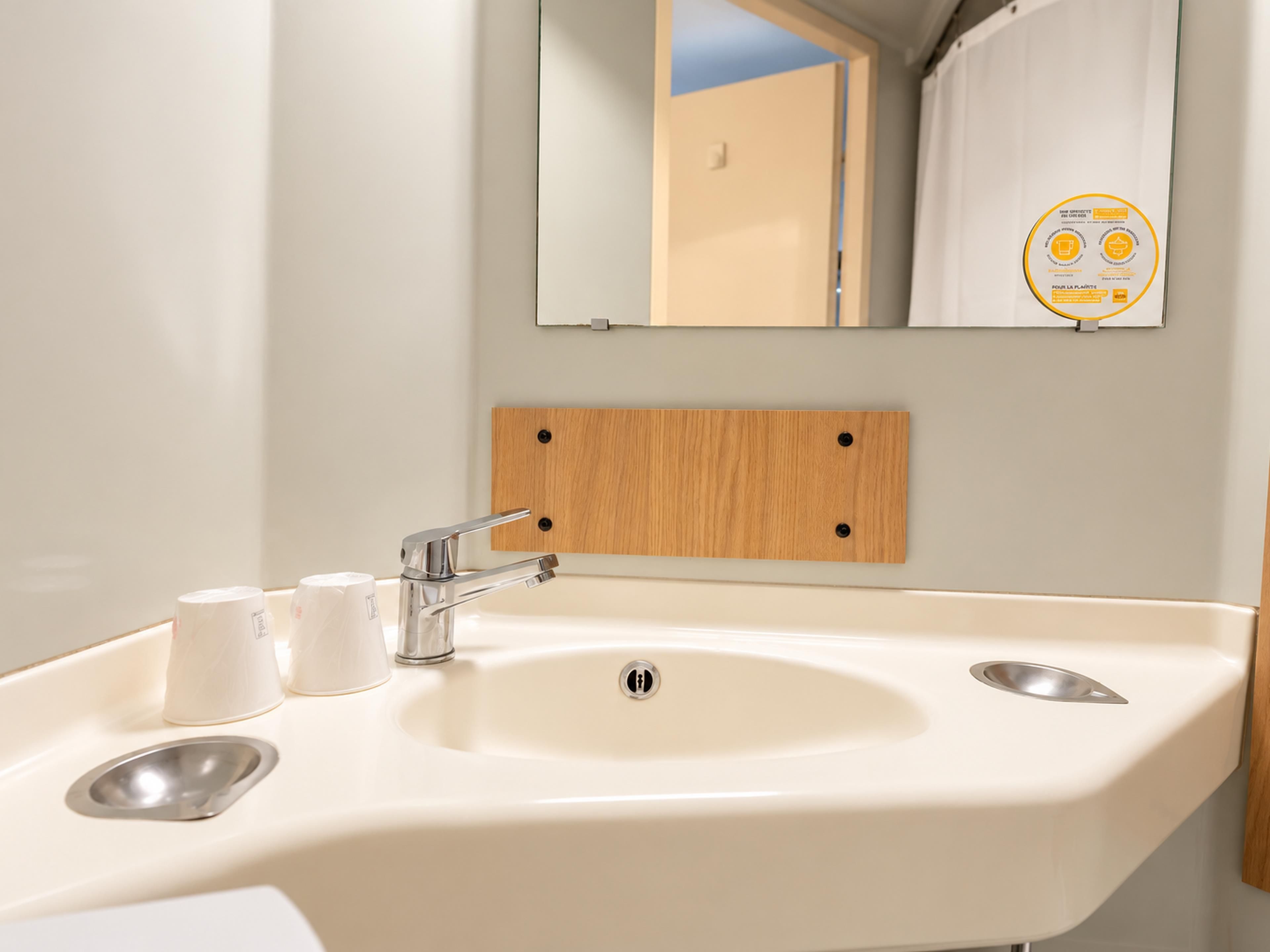 A bathroom with a white sink, two faucets, and a mirror above it.