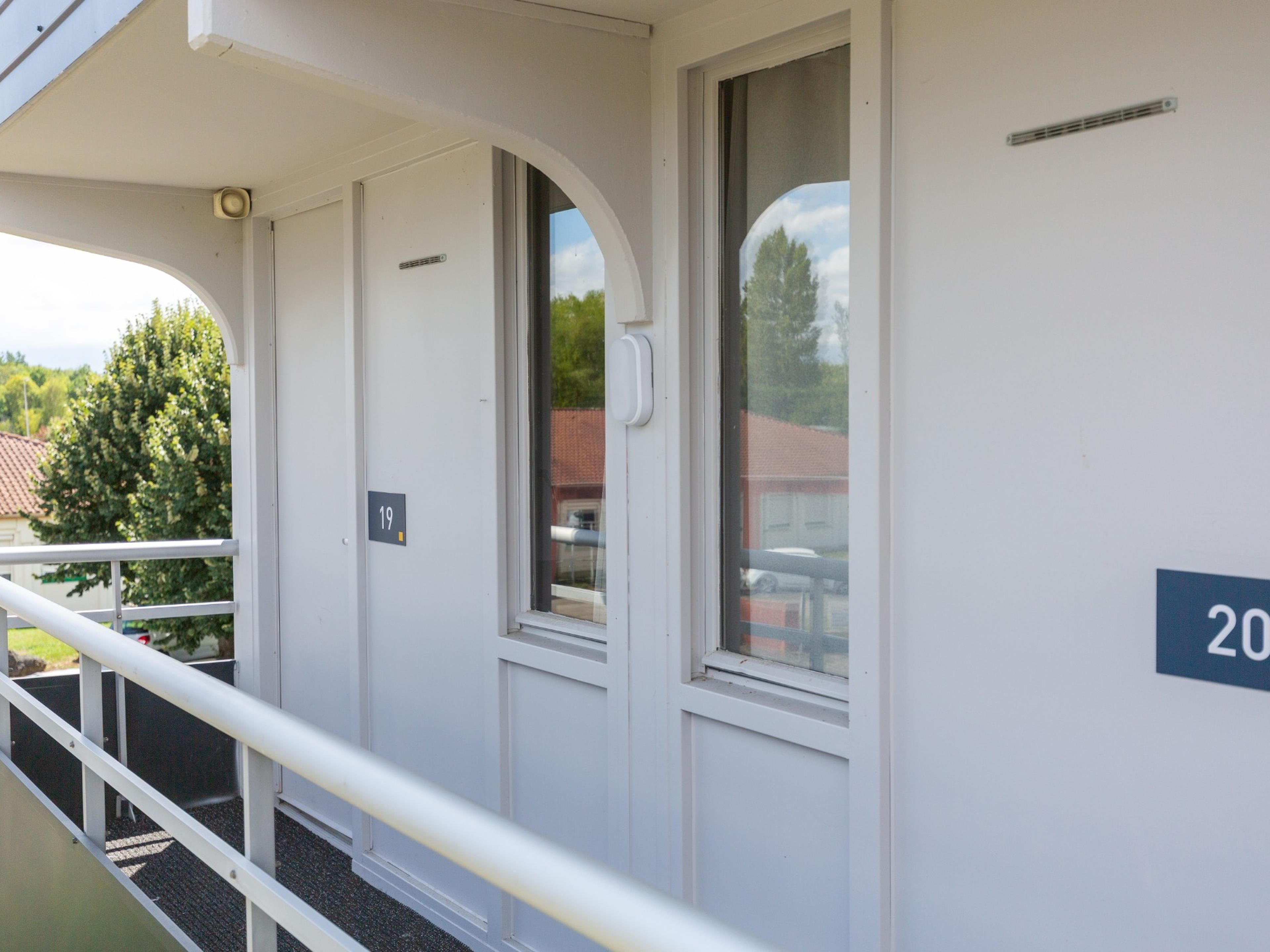 Ein Gebäude mit Balkon, einer Tür mit Klingelnummer und einem Fenster.