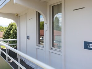 Een gebouw met een balkon, een deur met een nummer en een raam.