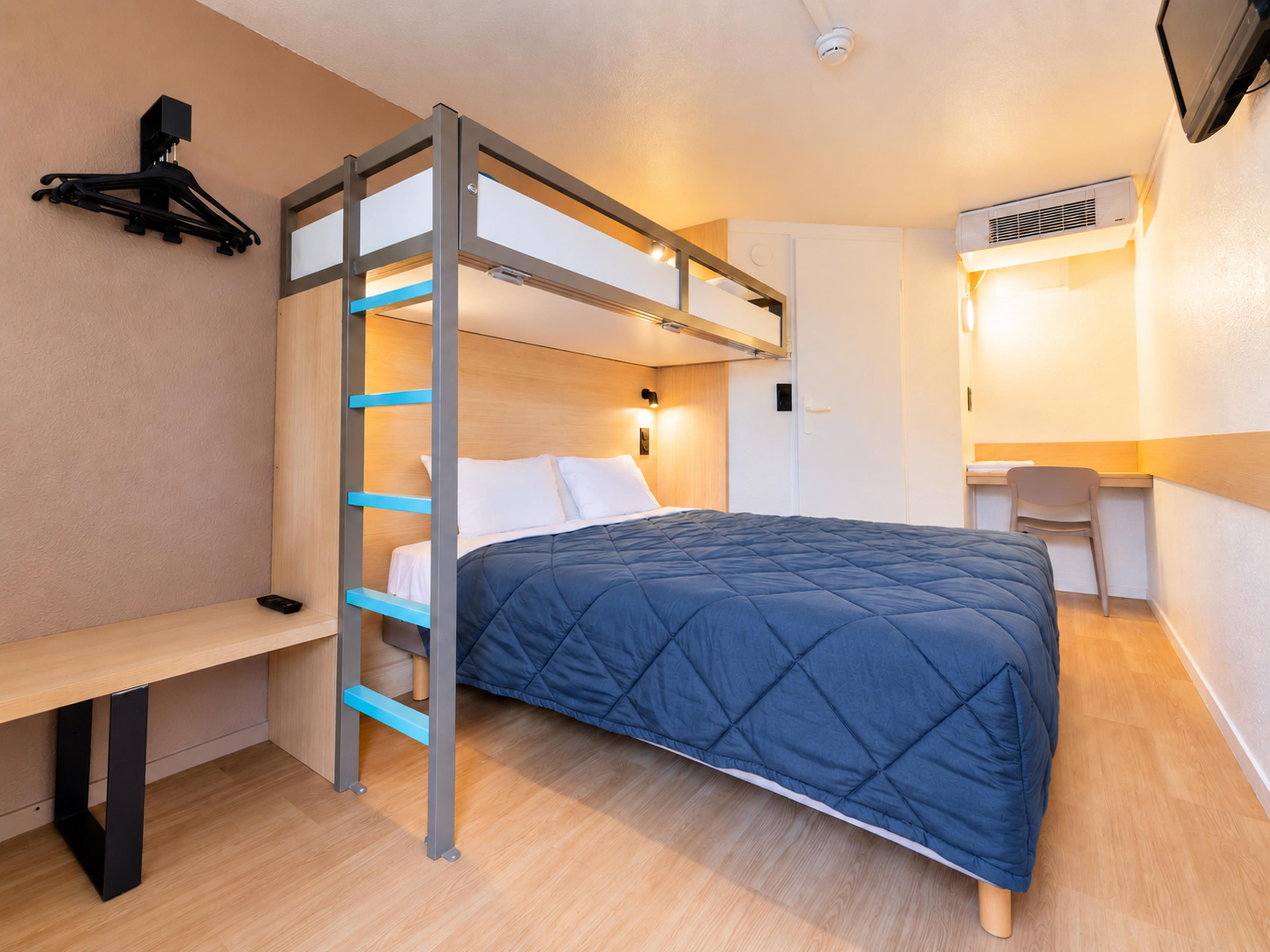 A bunk bed with a desk and chair, a wall-mounted TV, and an air conditioning unit.