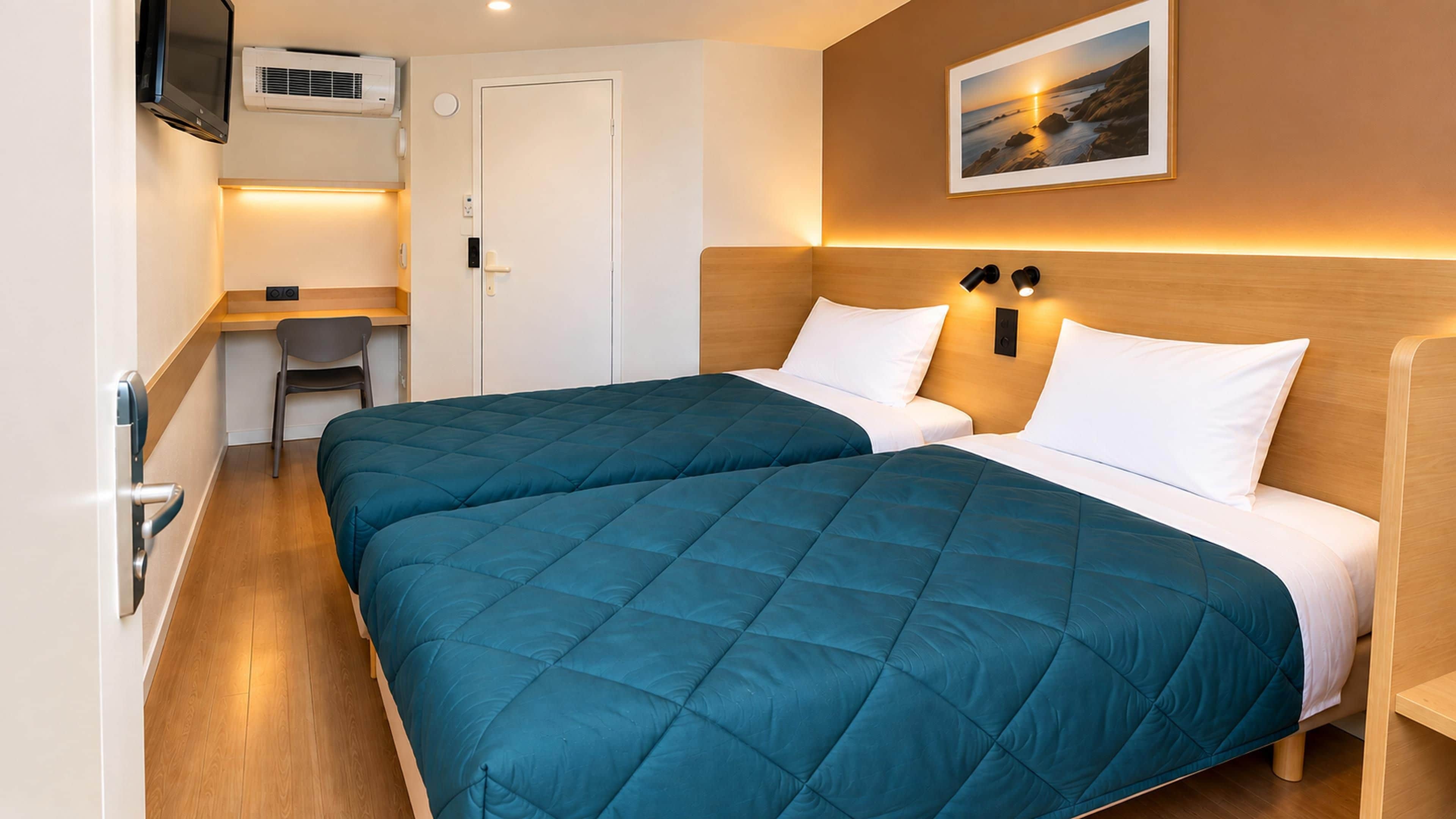A hotel room with two beds, a desk, and a television.