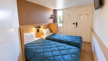 Una habitación de hotel con dos camas, un cabecero de madera, un televisor de pantalla plana montado en la pared y una puerta con picaporte.