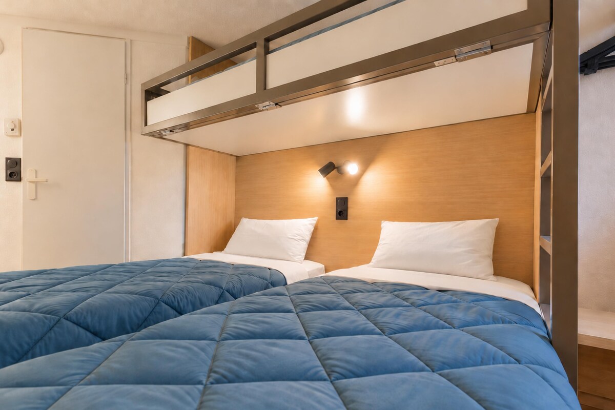 A hotel room with two beds, a wooden headboard, and a built-in shelf above the beds.
