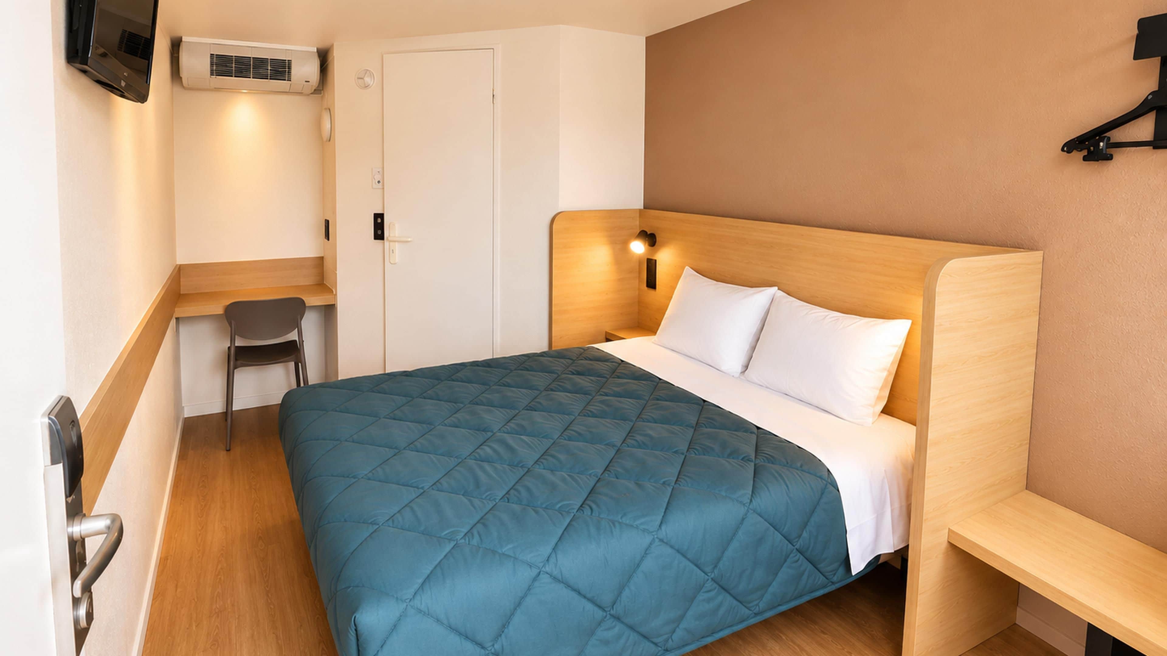 Een hotelkamer met een bed, een bureau, een stoel en een televisie.