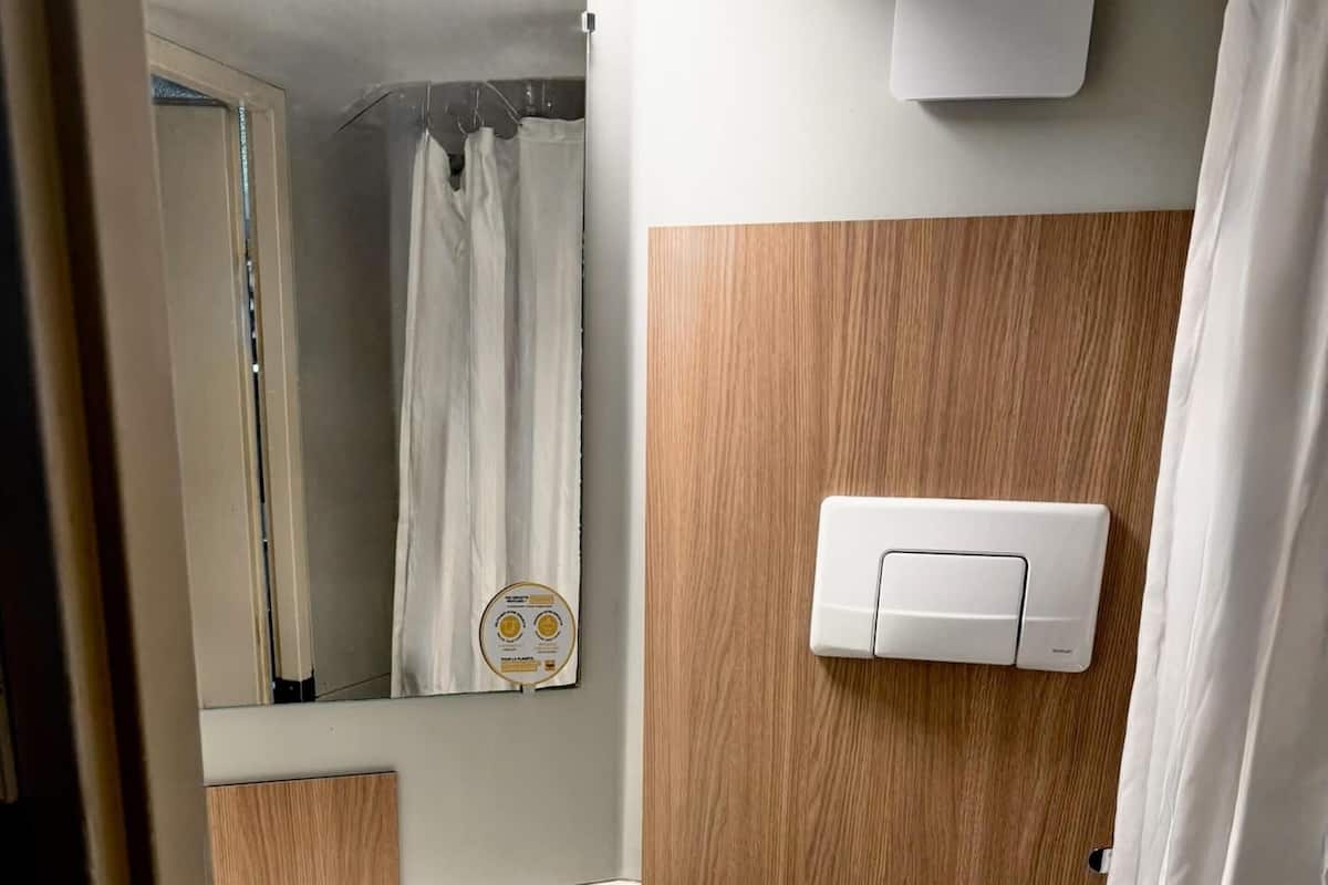 Een kleine badkamer met toilet, wastafel en spiegel.