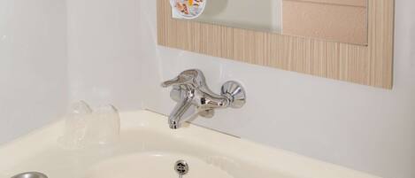 A bathroom with a white sink, a mirror, and a television mounted on the wall.