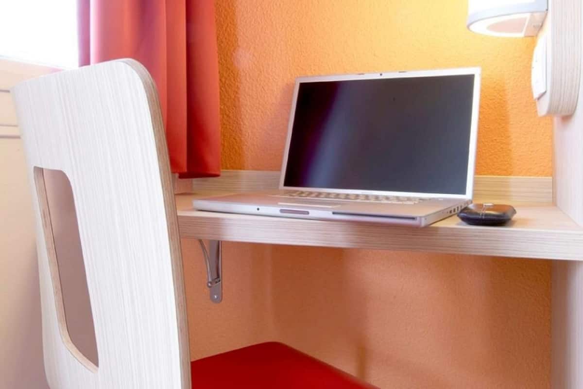 En bærbar computer på et træbord med en rød stol.