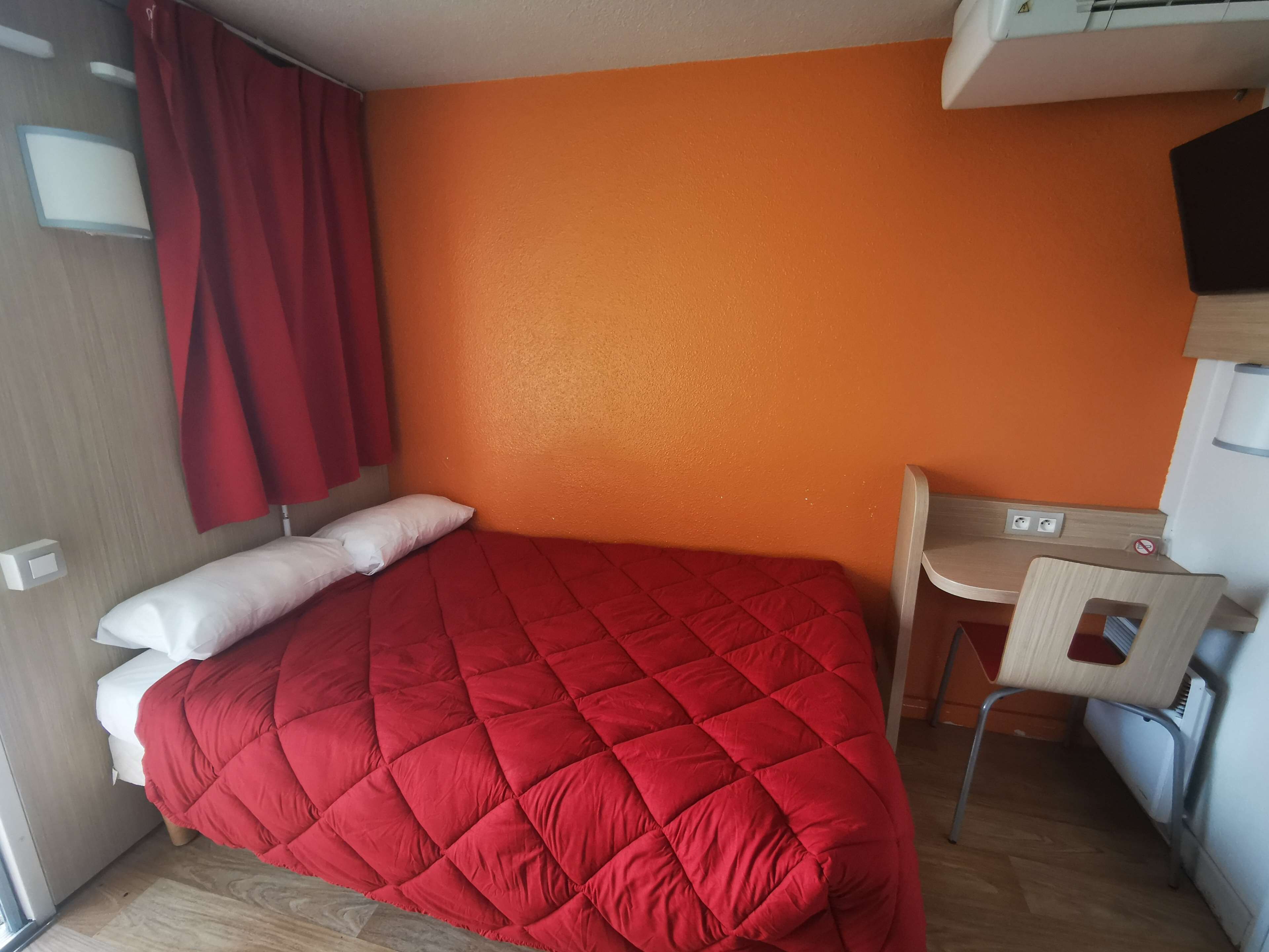 A room with a bed, a desk, and a chair.