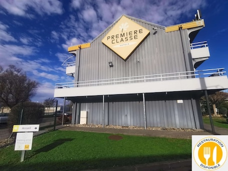 A hotel named PREMIERE CLASSE with a sign indicating private parking and a restaurant available.