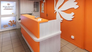 Un área de recepción con mostrador, una puerta con un letrero y una pared decorada con un diseño de hojas.